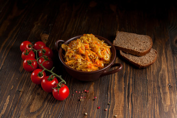stewed cabbage, bread and cherry tomatoes on a dark wooden table