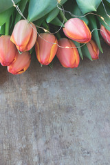 View of a beautiful bouquet of orange and yellow tulips decorated with led lights chain on old, rustic wooden background