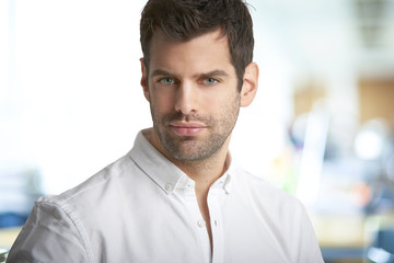 Fototapeta premium Young man portrait. Portrait of handsome young businessman looking at camera while standing at office.