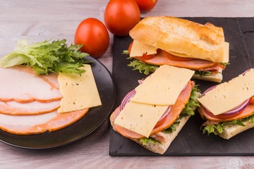 Sandwiches from baguette with bacon, cheese and tomatoes close-up