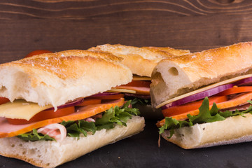 Sandwiches from baguette with bacon, cheese and tomatoes close-up