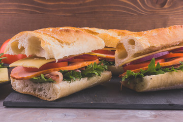 Sandwiches from baguette with bacon, cheese and tomatoes close-up