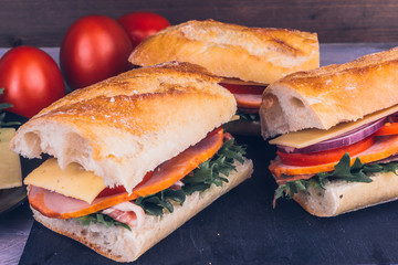 Sandwiches from baguette with bacon, cheese and tomatoes close-up