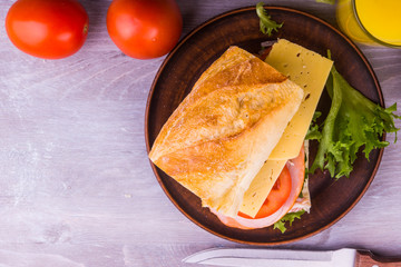 Sandwich with ham, cheese, lettuce, onions and tomatoes on a dark wooden background close-up, copy space