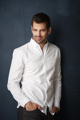 Handsome young man studio portrait. Studio portrait of confident young businessman wearing shirt and looking at camera whle standing at dark background with copy space.