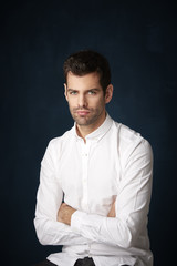 Obraz premium Handsome young man studio portrait. Studio portrait of confident young businessman wearing shirt and looking at camera whle standing at dark background with copy space.