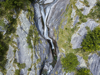 Vista aerea di una cascata in Val di Mello, una valle verde circondata da montagne di granito e boschi, ribattezzata la Yosemite Valley italiana. Val Masino, Valtellina, Sondrio. Italia