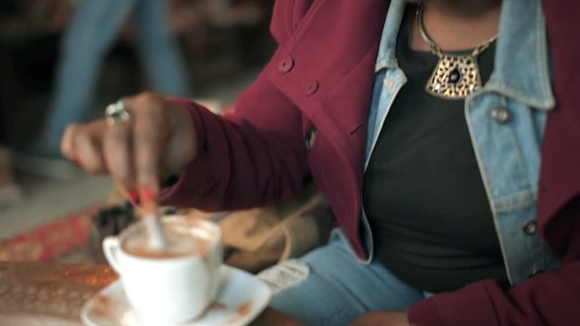 Beautiful African woman tastes sahlep with cinnamon first time and speaks with her friends around her.