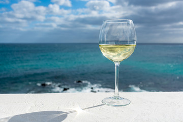 One glass of cold white wine served on outdoor terrace with sea view