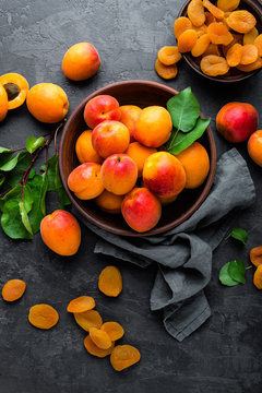 Fresh apricots with leaves and dried in bowl on table