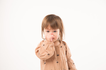 Cute little girl in beige dress isolated on white background. Portrait of happy little girl on white background. Sweet girl with curly hair.