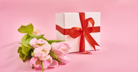 Valentines day background with pink tulips and gift box over pink background. Space for text