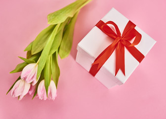 Valentines day background with pink tulips and gift box over pink background. Space for text