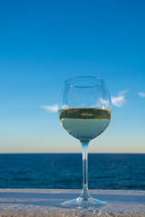 One glass of cold white wine served on outdoor terrace with sea view