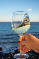 Tasting of glass of cold white wine on outdoor terrace with sea view