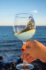 Poster Vin Tasting of glass of cold white wine on outdoor terrace with sea view