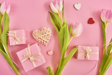Valentines Day background with pink tulips, red ribbon and gift box over pink background. Space for text