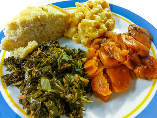 Southern comfort food in America. Close up serving of kale greens, candied yams, macaroni and...