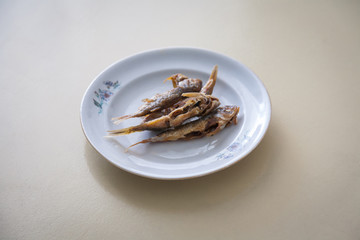 Minimalictic still life picture of a  plate  with small fried fishes