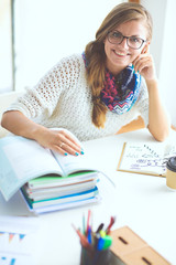 Young woman sitting at a desk among books. Student