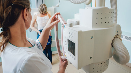 Radiologist and patient in a x-ray room. Classic ceiling-mounted x-ray system.