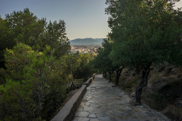 Stone pathway leading down the hill overlooking Malaga, Spain, Europe with trees on eiher