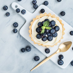Vanilla tartlets with blueberry berries on light background.