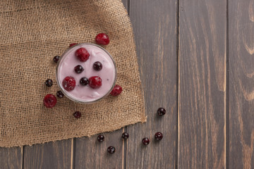 yogurt in a glass with berries on sacking and texture