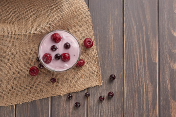 yogurt in a glass with berries on sacking and texture