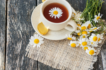 cup of herbal chamomile tea with fresh daisy flowers on wooden background. doctor treatment and prevention of immune concept, medicine - folk, alternative, complementary, traditional medicine 