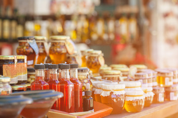 Honey in glass jars and bottles standing on the counter.