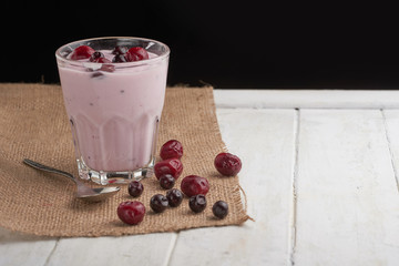 yogurt in a glass with berries on sacking and texture