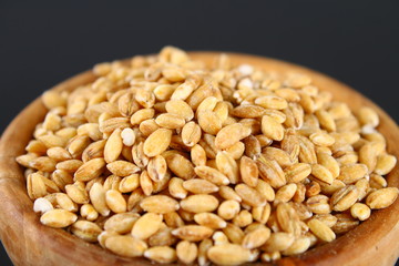 Dry pearl barley in a wooden bowl on a black chalkboard.