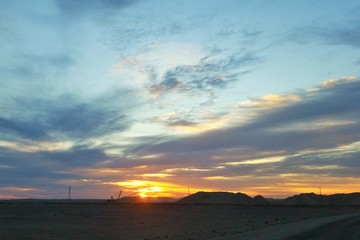 un beau lever de soleil sur une mine et au premier plan une excavatrice en activit&eacute;