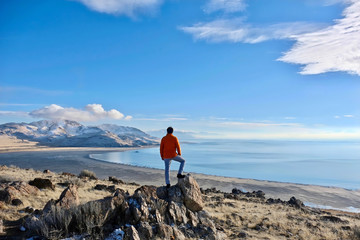 Great Salt Lake and Antelope Island in a winter day.  Man hiker on a cliff abover the lake enjoying the scenic views. Salt Lake City. Antelope Island State Park. Utah. United States.