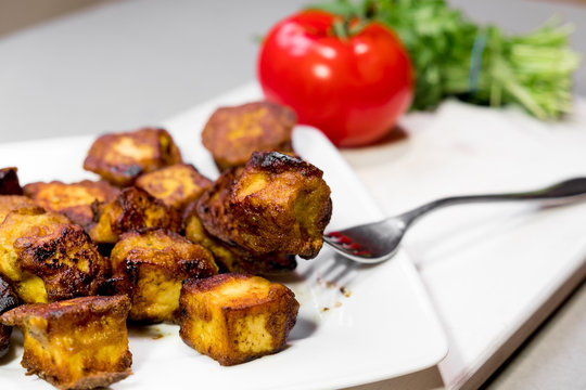 fried Indian slices of cottage cheese on a plate with tomato and rocula