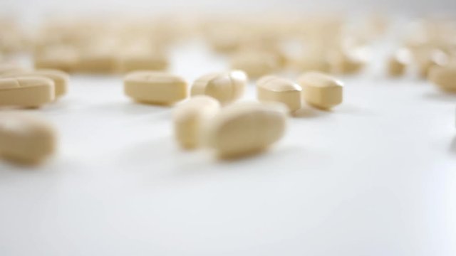 Spinning Vitamin B pills over white studio background 