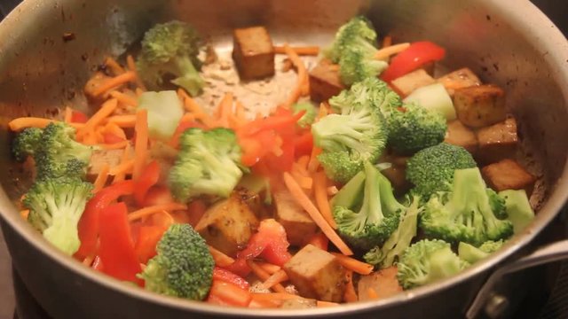 Tofu stir fry with vegetables cooking in pan	footage real time
