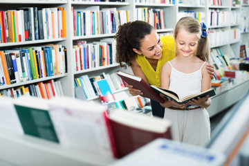 Cheerful woman with child reading open book