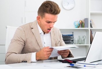 Frustrated manager doing paperwork at office.