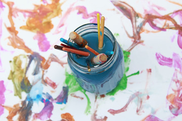 Paint brushes soaking in a glass jar of soapy water