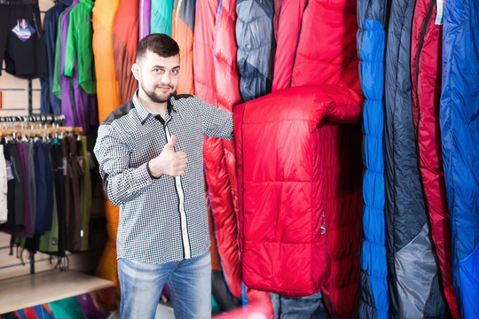 Positive guy choosing new sleeping bag in shop