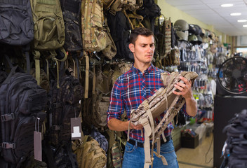 guy looking camouflage backpack in army store