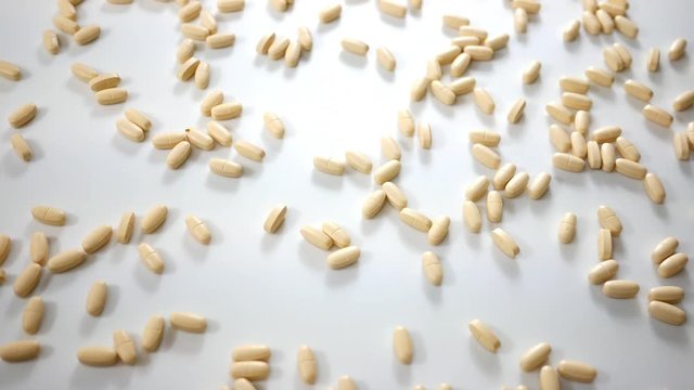 Spinning Vitamin B pills over white studio background - Above Angle