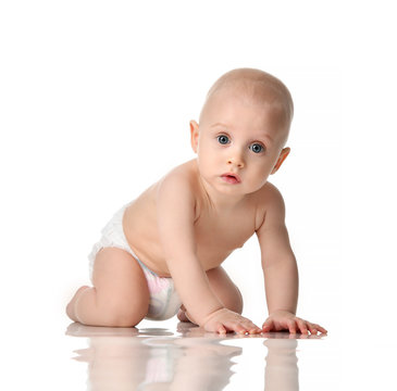 Nine month old infant baby boy with blue eyes wearing  diaper crawling