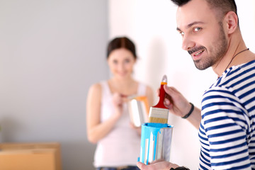 Portrait of happy smiling young couple painting interior wall of new house. young couple