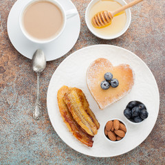 A stack of delicious pancakes with honey, coffee and blueberries on a on a rusty red background. Great Breakfast for Valentine's day. Top view