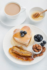 A stack of delicious pancakes with honey, coffee and blueberries on a light blue background. Great Breakfast for Valentine's day
