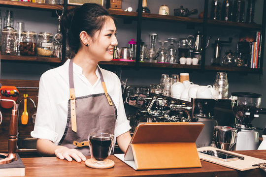 Barista woman using digital tablet compute in coffee shop counter bar