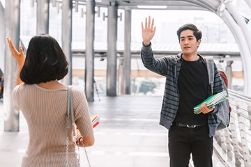 Happy students waving and saying hello with friend